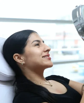 Paciente sonriendo frente al espejo en la cabina de Dermostética